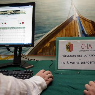 Des personnes regardant les résultats de votations en 2016 à Genève. [Keystone - Salvatore Di Nolfi]