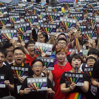 "Les votes ne peuvent pas être battus": des partisans du mariage homosexuel se mobilisent devant le Parlement taïwanais, à Taipei. [Keystone - Chiang Ying-yin]