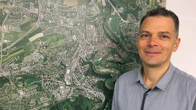 Raphaël Casazza, ingénieur EPFL en environnement, devant la carte de Fribourg. [RTS - Jean de Preux]