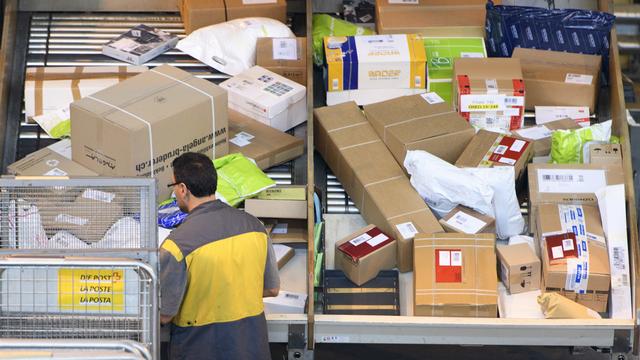 Un employé de La Poste trie des colis au centre de Daillens, dans le canton Vaud. [Laurent Gillieron]