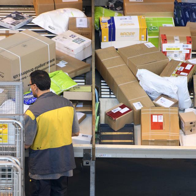 Un employé de La Poste trie des colis au centre de Daillens, dans le canton Vaud. [Laurent Gillieron]