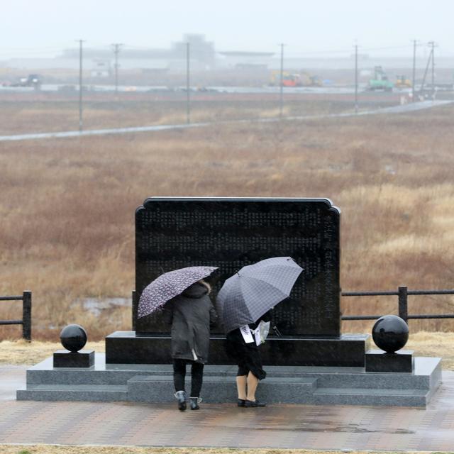 Deux personnes prient devant le mémorial de Fukushima, huit ans après le séisme meurtrier. [Keystone - EPA/Jiji Press Japan]