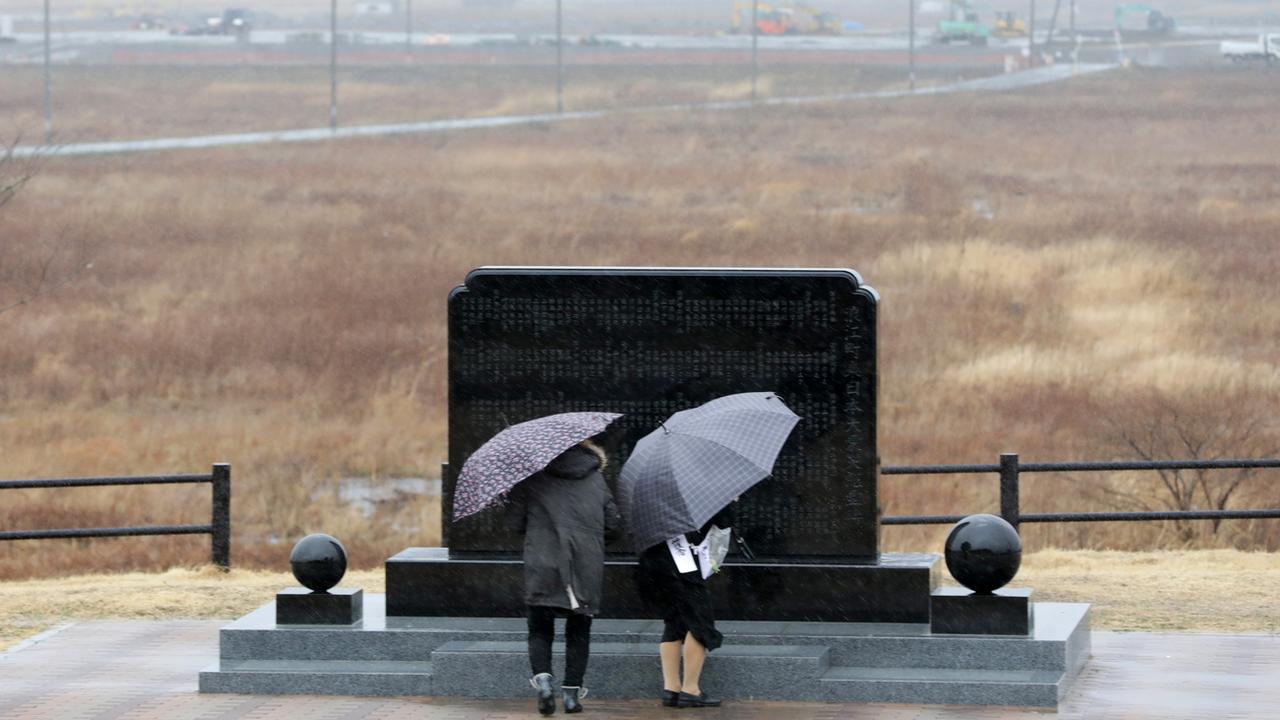 Deux personnes prient devant le mémorial de Fukushima, huit ans après le séisme meurtrier. [Keystone - EPA/Jiji Press Japan]