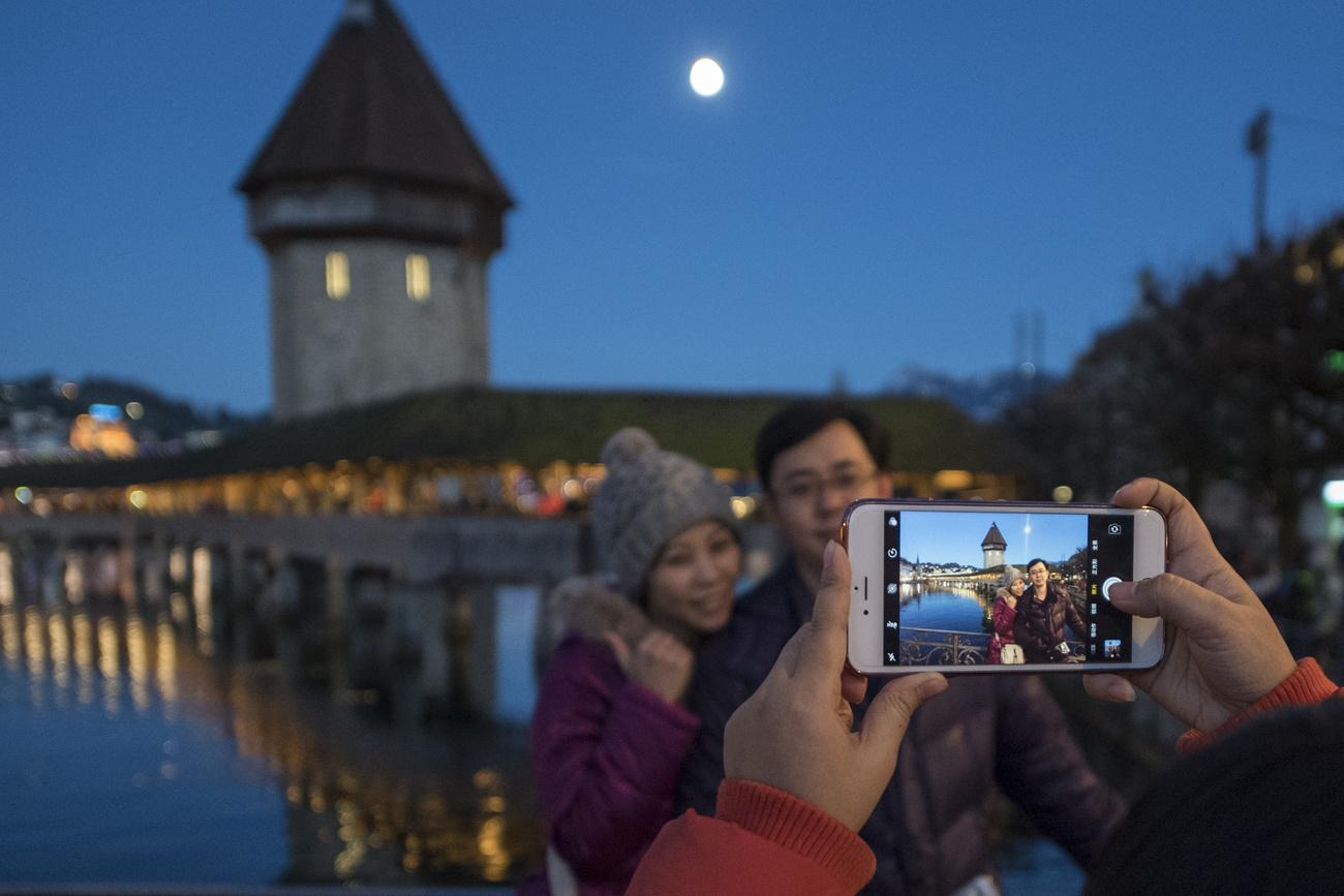 Des touristes asiatiques photographiés devant le pont de Lucerne. [Keystone - Urs Flueeler]