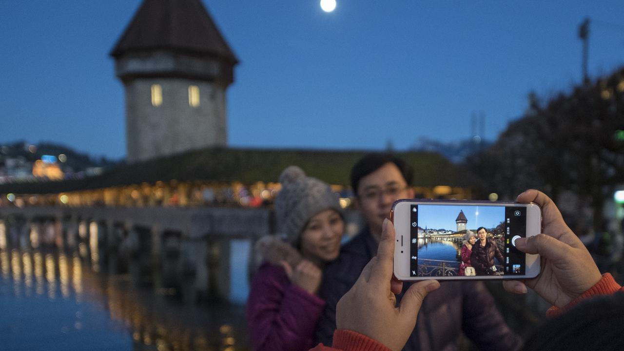 Des touristes asiatiques photographiés devant le pont de Lucerne. [Keystone - Urs Flueeler]