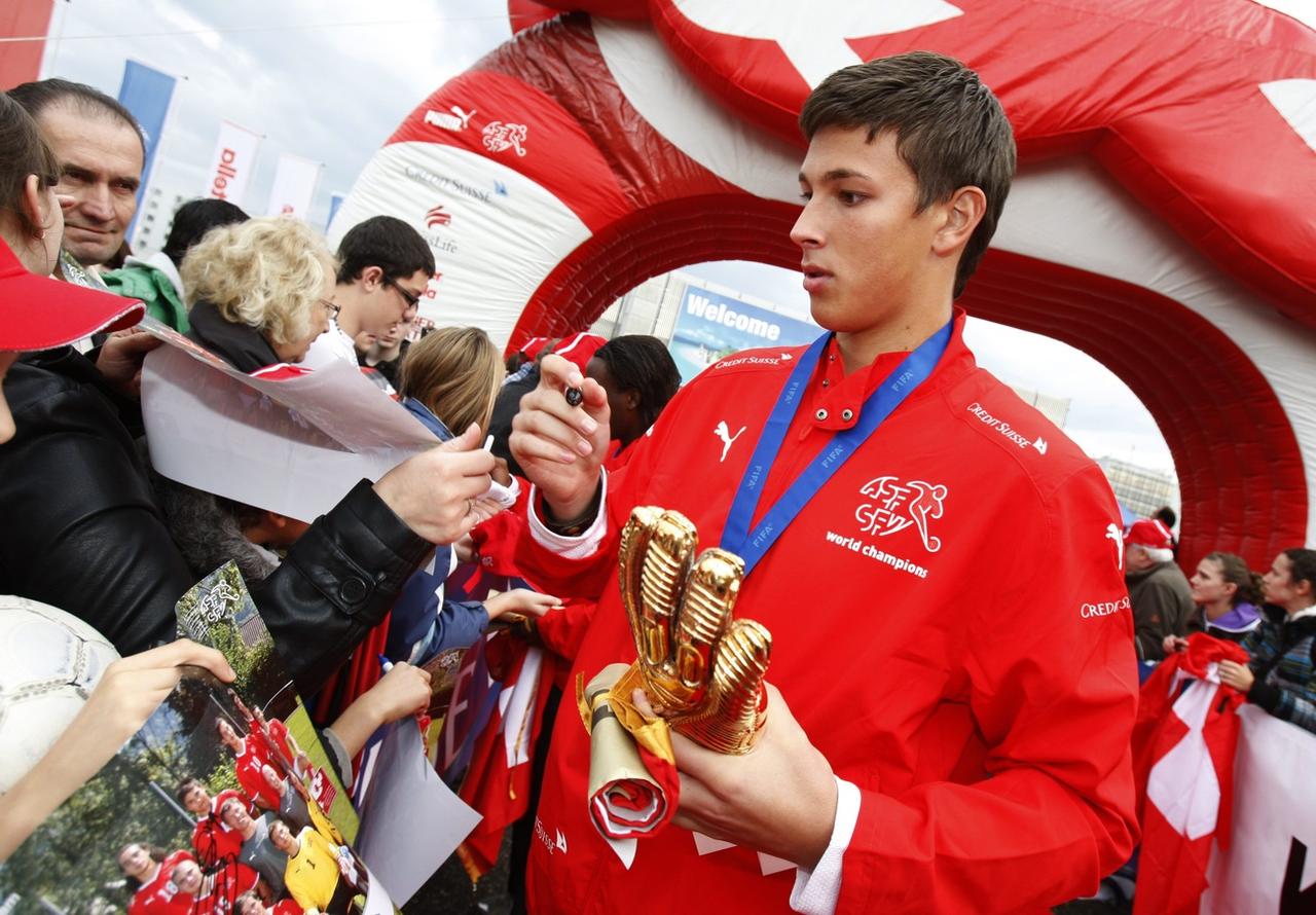 Benjamin Siegrist, avec le "gant d'or" du meilleur gardien du tournoi dans sa main gauche. [Keystone - STEFFEN SCHMIDT]