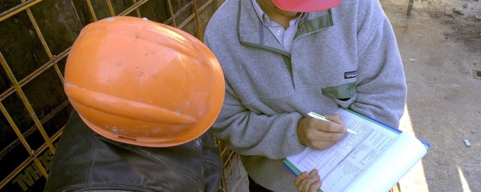 Un inspecteur cantonal de l'Emploi en visite sur un chantier. [Keystone - Andrée-Noëlle Pot]