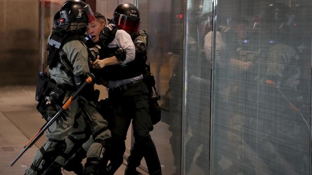 La police anti-émeute brutalise un homme à Hong-Kong, le 12 novembre 2019. [AP Photo/Keystone - Ng Han Guan]