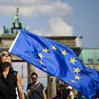 Une femme portant un drapeau européen devant la porte de Brandebourg à Berlin. [Keystone - AP Photo/Markus Schreiber]