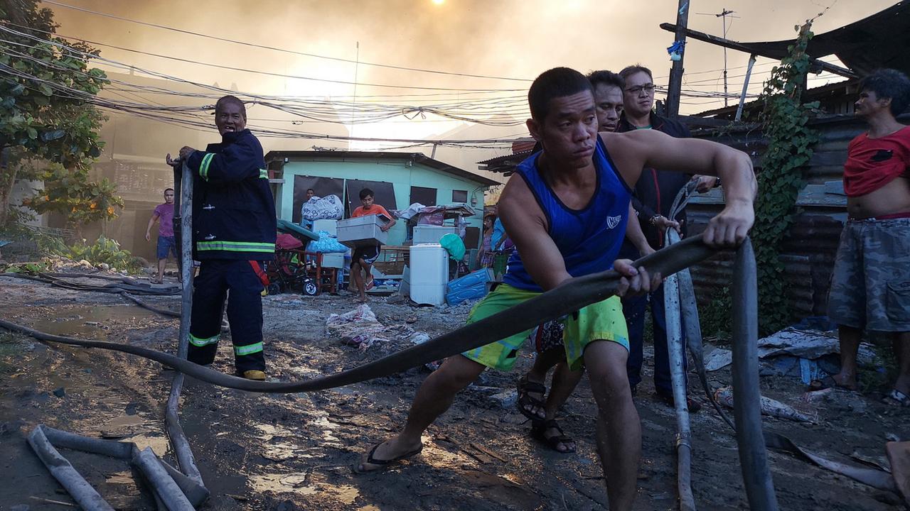Des habitants des Philippines tentent de maîtriser un incendie près de Manille. (image d'illustration) [Keystone - EPA/STR]
