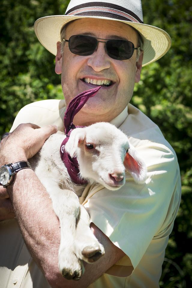 Le Conseiller fédéral Guy Parmelin porte un agneau dans ses bras lors de la journée "Portes ouvertes à la ferme". [Keystone - Jean-Christophe Bott]