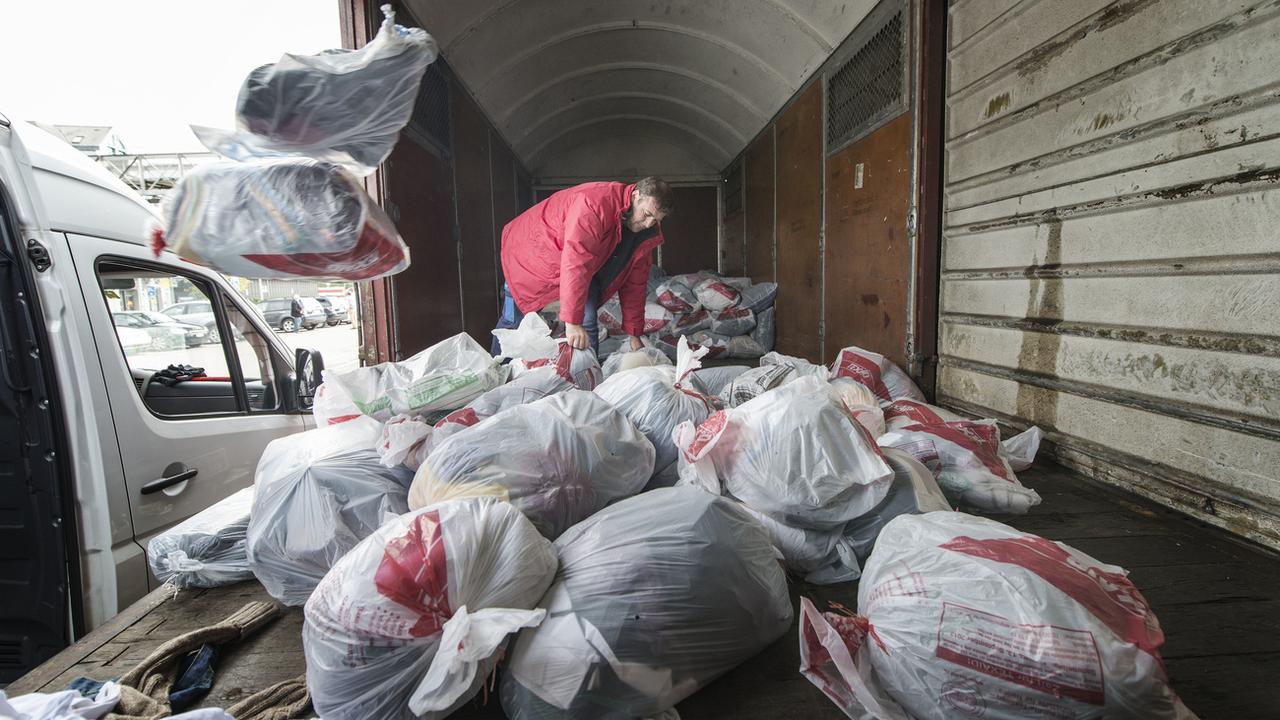 Un employé de Texaid procède au ramassage des sacs de vêtements usagés. [Christian Beutler - Keystone]