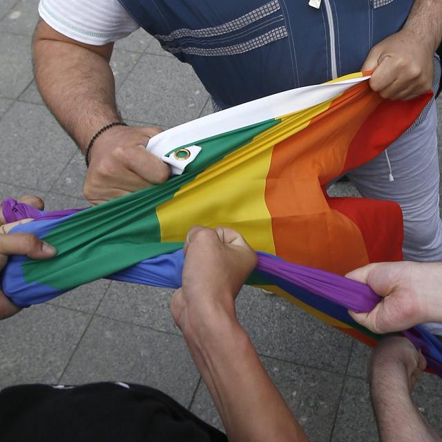 Des hommes russes tiennent un drapeau arc-en-ciel pendant un manifestation LGBT+ (Moscou, mai 2015). [Keystone/epa - Sergei Ilnitsky]