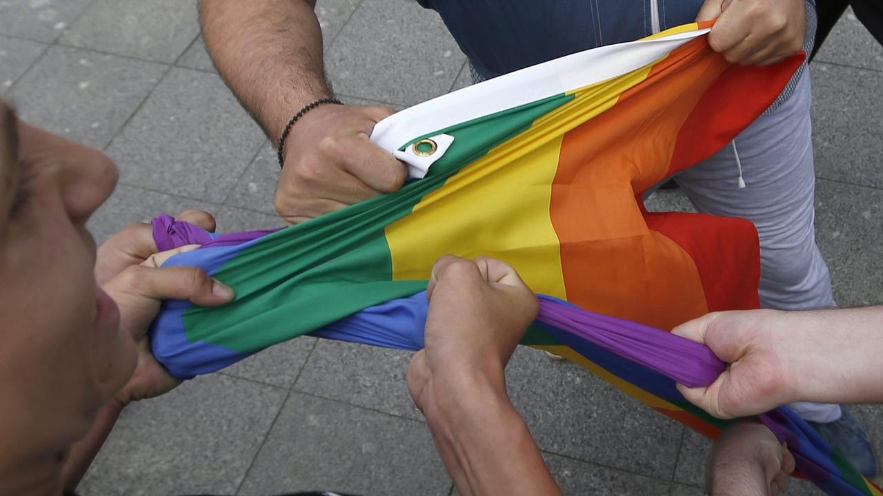 Des hommes russes tiennent un drapeau arc-en-ciel pendant un manifestation LGBT+ (Moscou, mai 2015). [Keystone/epa - Sergei Ilnitsky]