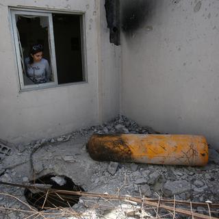 Une journaliste examine une maison endommagée: celle-ci a reçu la visite de l'Organisation pour l'Interdiction des Armes Chimiques. Douma, Syrie, 23 avril 2019. [Reuters - Ali Hashisho]