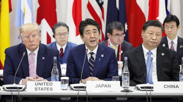 Donald Trump et Xi Jinping entourent le premier ministre japonais Shinzo Abe lors du discours d'ouverture du G20. [Keystone/EPA]
