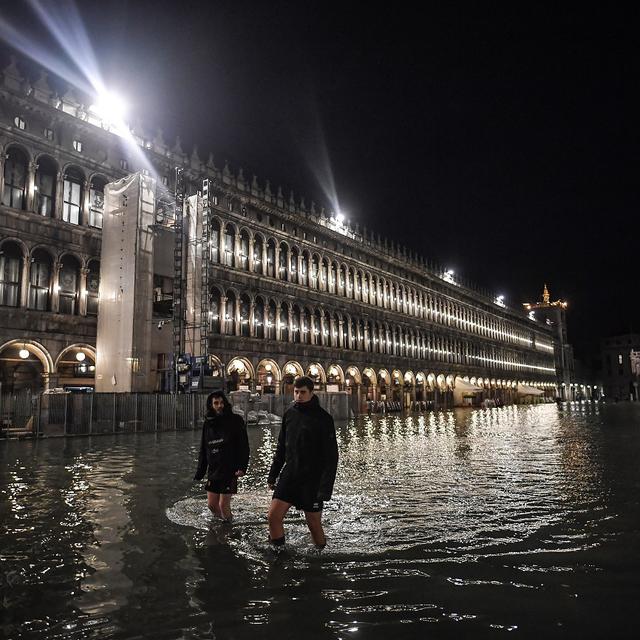 Des passants affrontent l'exceptionnelle "acqua alta" sur la place Saint Marc à Venise. [Marco Bertorello - AFP]