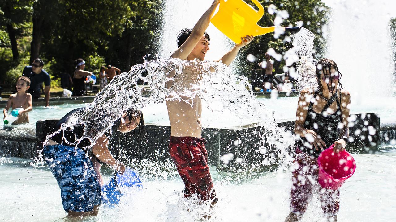 Des jeunes participent à une bataille d'eau dans la fontaine du parc de Milan à Lausanne. [Keystone - Jean-Christophe Bott]