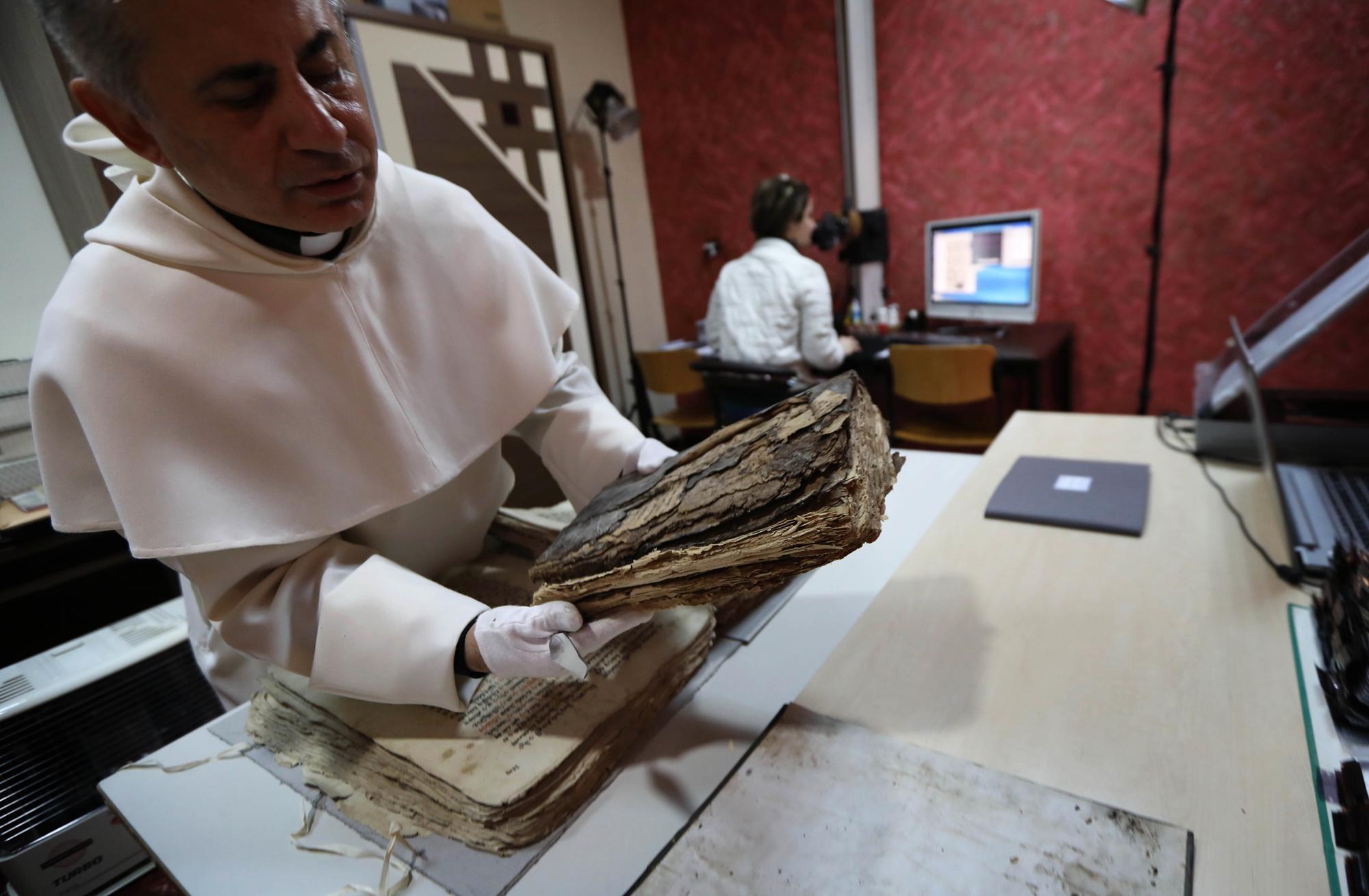 Le Père Michaeel Najeeb tient un livre ancien et abîmé au Centre de Digitalisation des manuscrits à Arbil, capitale de la région autonome du Kurdistan, le 1er mars 2018. [AFP - SAFIN HAMED]