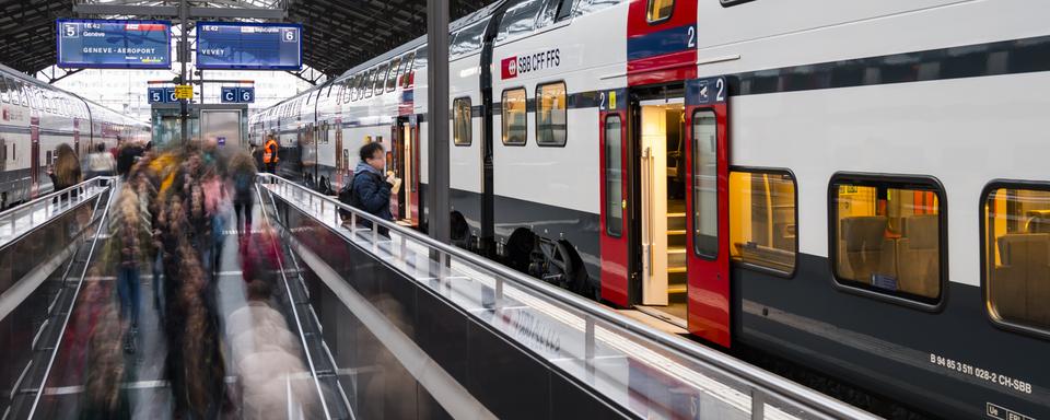 Des voyageurs et des pendulaires circulent sur un quai devant un train CFF SBB le 14 novembre 2018 dans la gare de Lausanne. [Keystone - Jean-Christophe Bott]