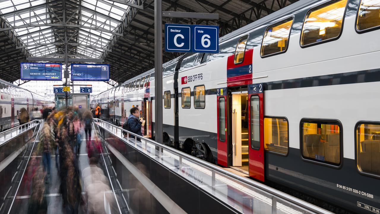 Des voyageurs et des pendulaires circulent sur un quai devant un train CFF SBB le 14 novembre 2018 dans la gare de Lausanne. [Keystone - Jean-Christophe Bott]