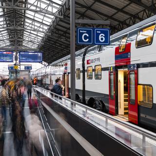 Des voyageurs et des pendulaires circulent sur un quai devant un train CFF SBB le 14 novembre 2018 dans la gare de Lausanne. [Keystone - Jean-Christophe Bott]
