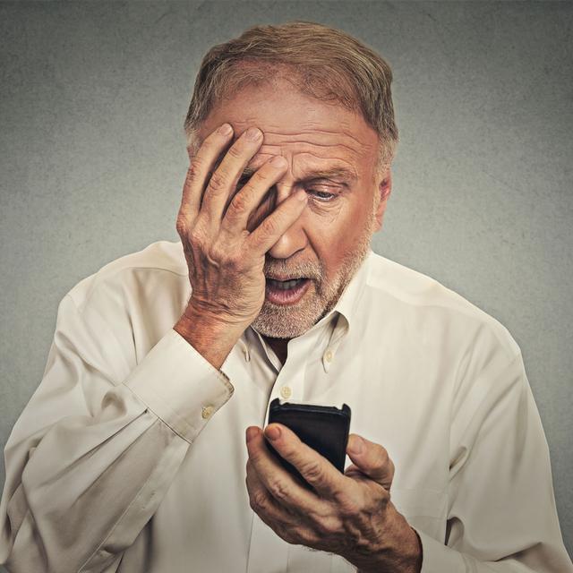 Un homme tient son smartphone dans la main et regarde l'écran, choqué. [Depositphotos - SIphotography]