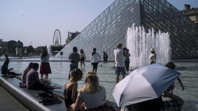Des Parisiens se rafraîchissent dans la fontaine du Louvre. [AP/Keystone - Rafael Yaghobzadeh]