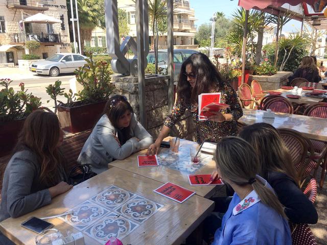 Une militante en faveur du boycott des élections législatives israéliennes distribue des tracts dans un café de Haïfa. [Reuters - Rami Ayyub]