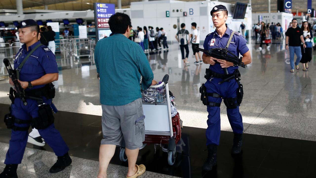 La police armée dans le hall des départs de l'aéroport de Hong Kong. [Reuters - Thomas Peter]