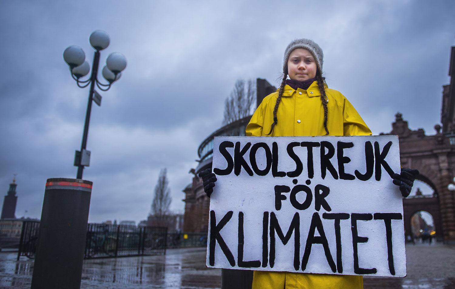 Greta Thunberg tient une pancarte appelant à la grève pour le climat. [AFP - Hanna Franzen]