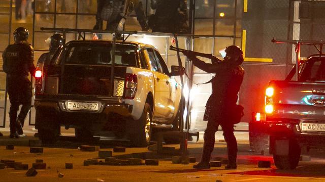 Un policier armé d'un fusil semble mettre en joue des manifestants à Minsk, lundi 10.08.2020. [AP/Keystone]