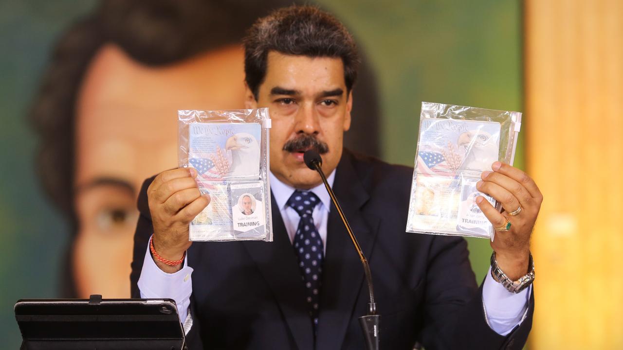 Le président vénézuélien Nicolas Maduro brandit les passeports et cartes professionnelles de Silvercorp des deux Américains arrêtés à la télévision, le 6 mai 2020. [Communication présidentielle/AP/Keystone]