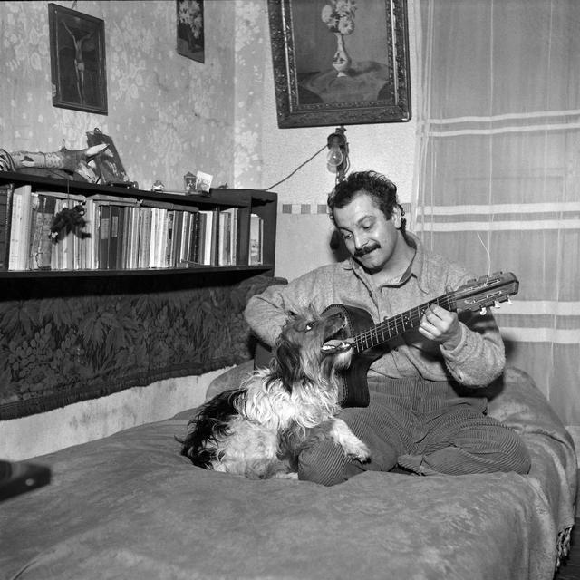 Le chanteur français Georges Brassens pose avec un chien, dans un lieu tenu secret, en janvier 1953. [AFP - Henri Elwing]