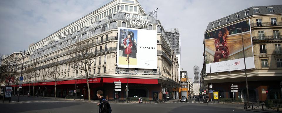 Un homme devant les Galeries Lafayette à Paris, vide, le 20 mars 2020. [AFP - Thibault Camus]