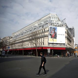 Un homme devant les Galeries Lafayette à Paris, vide, le 20 mars 2020. [AFP - Thibault Camus]