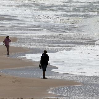 Des promeneurs sur une plage à Biarritz. [Keystone - AP Photo/Bob Edme]