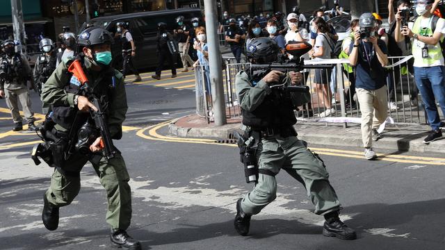 Des policiers prêts à tirer du spray au poivre dans une rue de Hong Kong. [Keystone - EPA / Jérôme Favre]