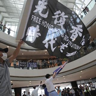 Les protestations continuent à Hong Kong, tandis que les batailles de visas se poursuivent entre la Chine et les États-Unis. [Keystone - Kin Cheung]