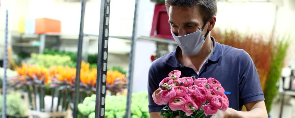 En Autriche, une réouverture partielle de l'économie permet aux commerçants de reprendre leur activité, comme ce fleuriste, équipé d'un masque et photographié à Vienne. [Reuters - Lisi Niesner]