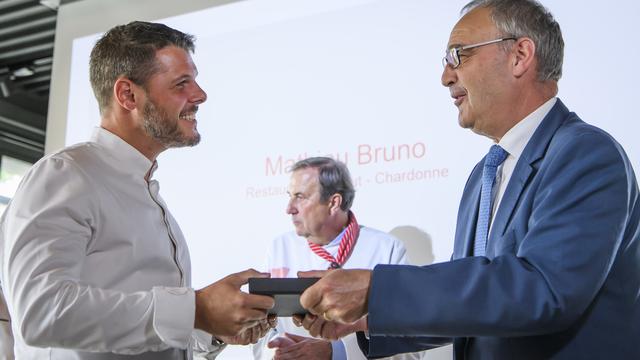 Le chef Mathieu Bruno (à gauche), du restaurant Là-Haut à Chardonne (VD), se voit remettre le Mérite culinaire par le conseiller fédéral Guy Parmelin. [KEYSTONE - Anthony Anex]