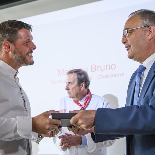 Le chef Mathieu Bruno (à gauche), du restaurant Là-Haut à Chardonne (VD), se voit remettre le Mérite culinaire par le conseiller fédéral Guy Parmelin. [KEYSTONE - Anthony Anex]