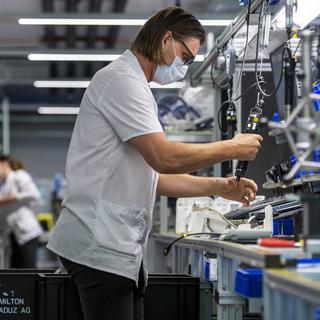Une technicienne sur une chaîne de montage d'appareils respiratoires, dans l'entreprise Hamilton Ems, le 20 avril 2020. [Keystone - Alessandro della Valle]