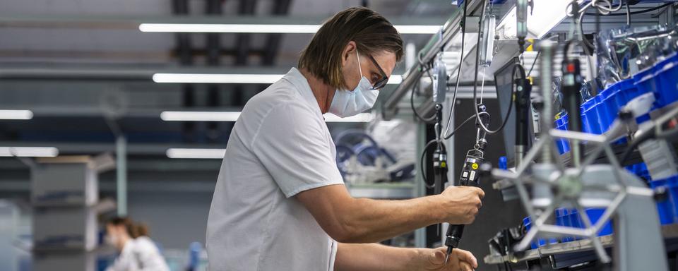 Une technicienne sur une chaîne de montage d'appareils respiratoires, dans l'entreprise Hamilton Ems, le 20 avril 2020. [Keystone - Alessandro della Valle]