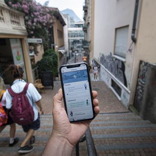 Une personne tient son smartphone avec l'application SwissCovid, le 25 juin 2020 à Lugano. [Keystone - Pablo Gianinazzi]