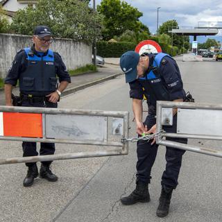Deux gardes frontières ouvrent la barrière qui barrait l'accès à Thônex près de Genève. [Keystone - Martial Trezzini]