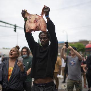 Un homme brandit une tête de porc à destination des policiers, à Minneapolis, le 27 mai 2020. [Star Tribune/AP/Keystone - Jeff Wheeler]