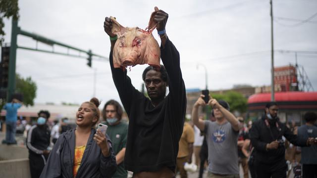 Un homme brandit une tête de porc à destination des policiers, à Minneapolis, le 27 mai 2020. [Star Tribune/AP/Keystone - Jeff Wheeler]