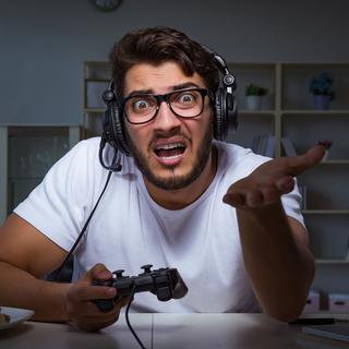 Un homme qui joue aux jeux vidéos s'énerve après son ordinateur. [Depositphotos - Elnur_]