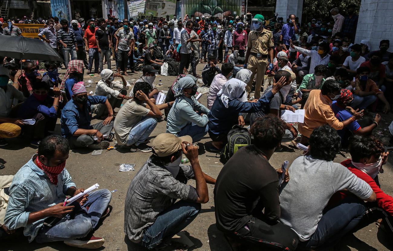 Des travailleurs migrants attendant le 23 mai à Bombay d'emprunter un des transports organisés par les autorités pour les ramener dans leur village. [Keystone - EPA/DIVYAKANT SOLANKI]